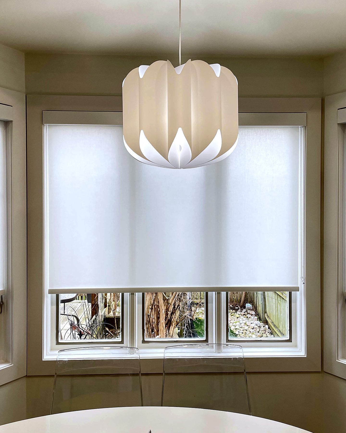 Bay window with light-filtering roller shades above a breakfast table