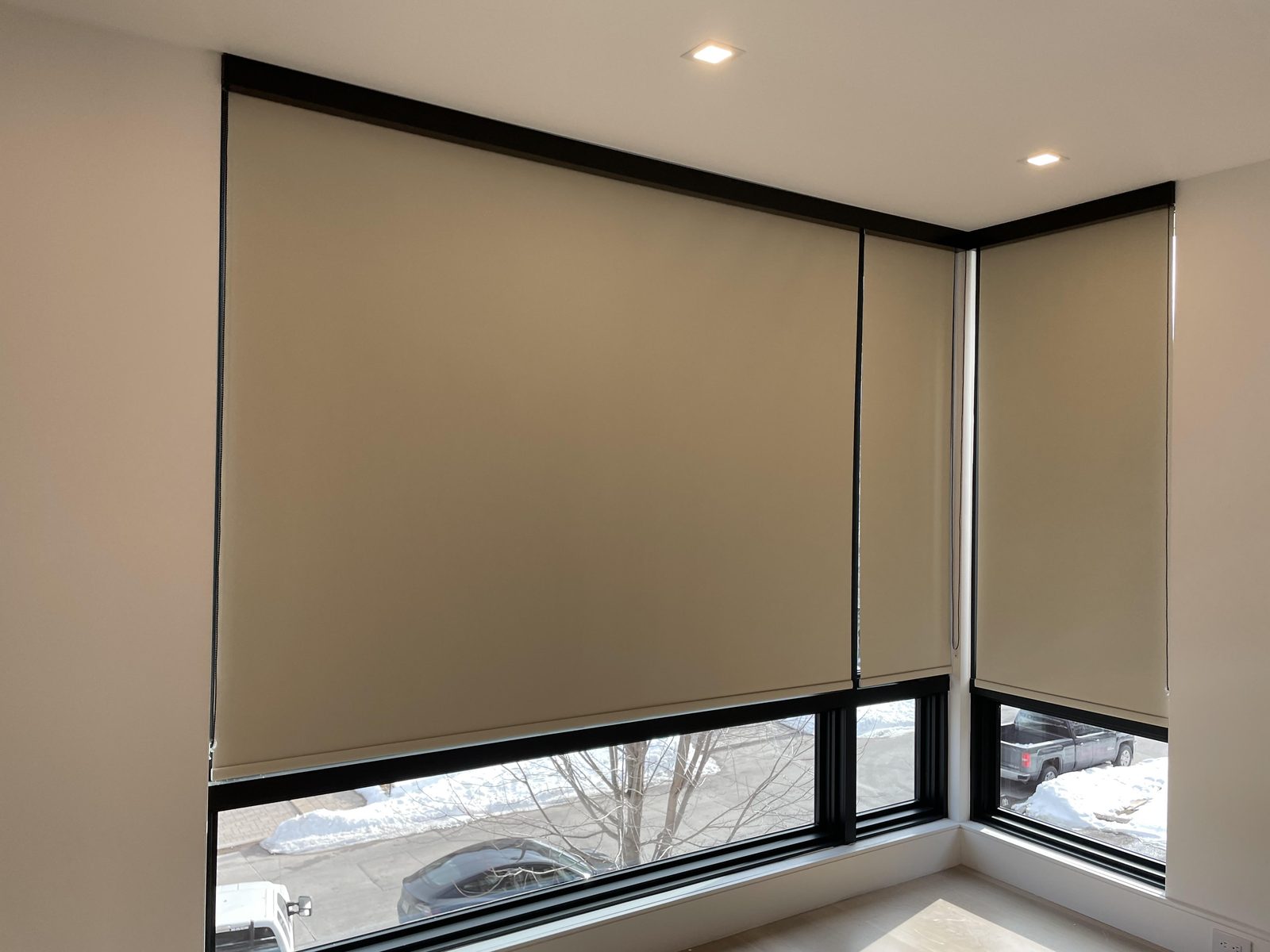 Corner windows fitted with opaque blackout roller shades in black cassettes