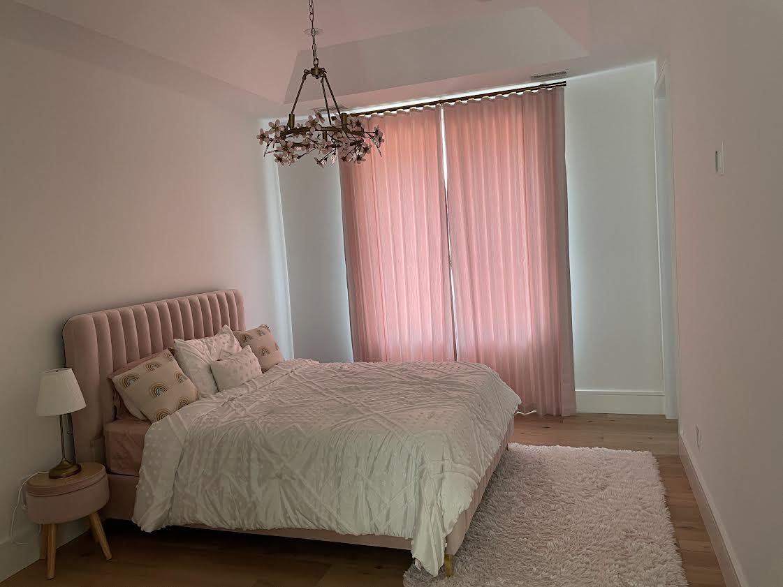 Bedroom with blush sheer drapery on a ceiling track at a corner window