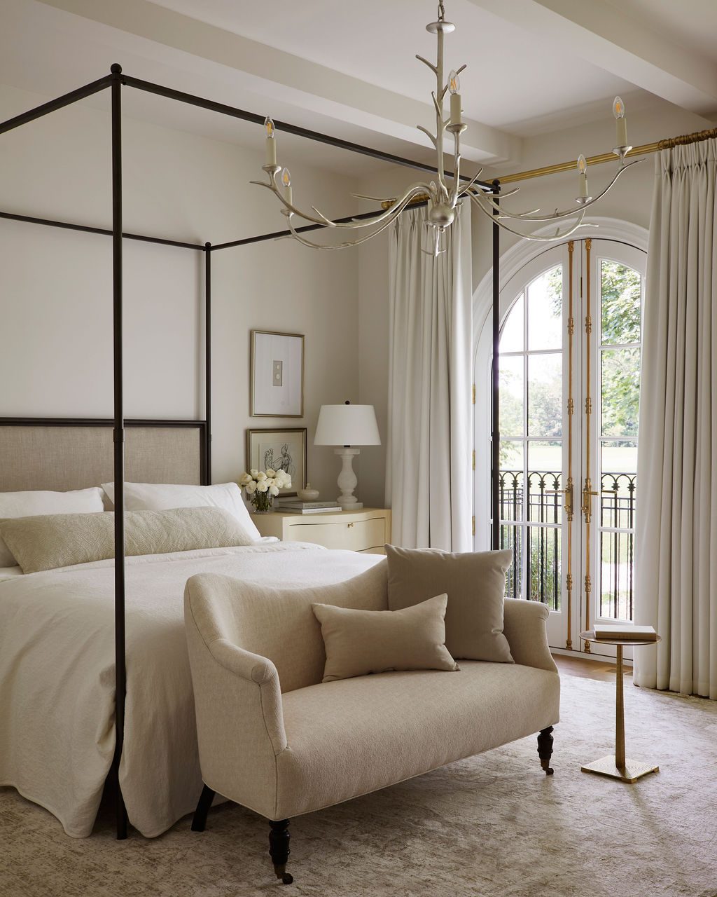 Principal bedroom with ivory drapery panels at an arched French door