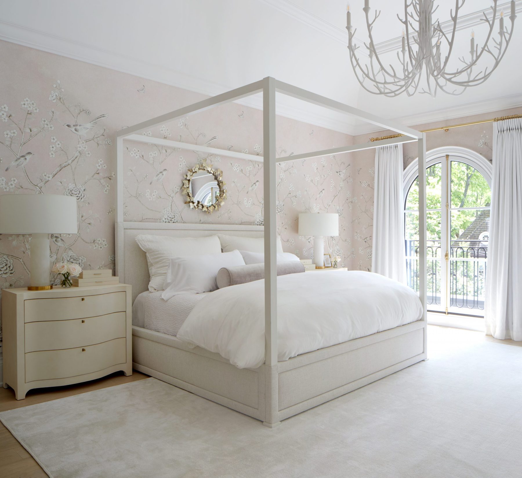 Bedroom with a canopy bed and floor-to-ceiling sheer drapery at an arched door