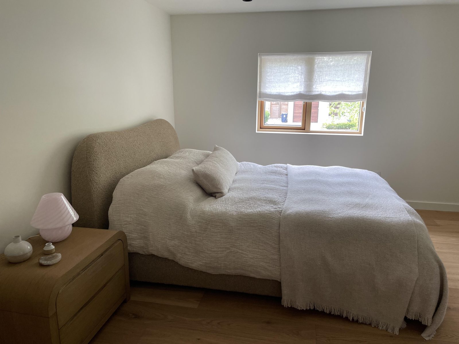 Bedroom with a white sheer linen relaxed Roman shade at a small window