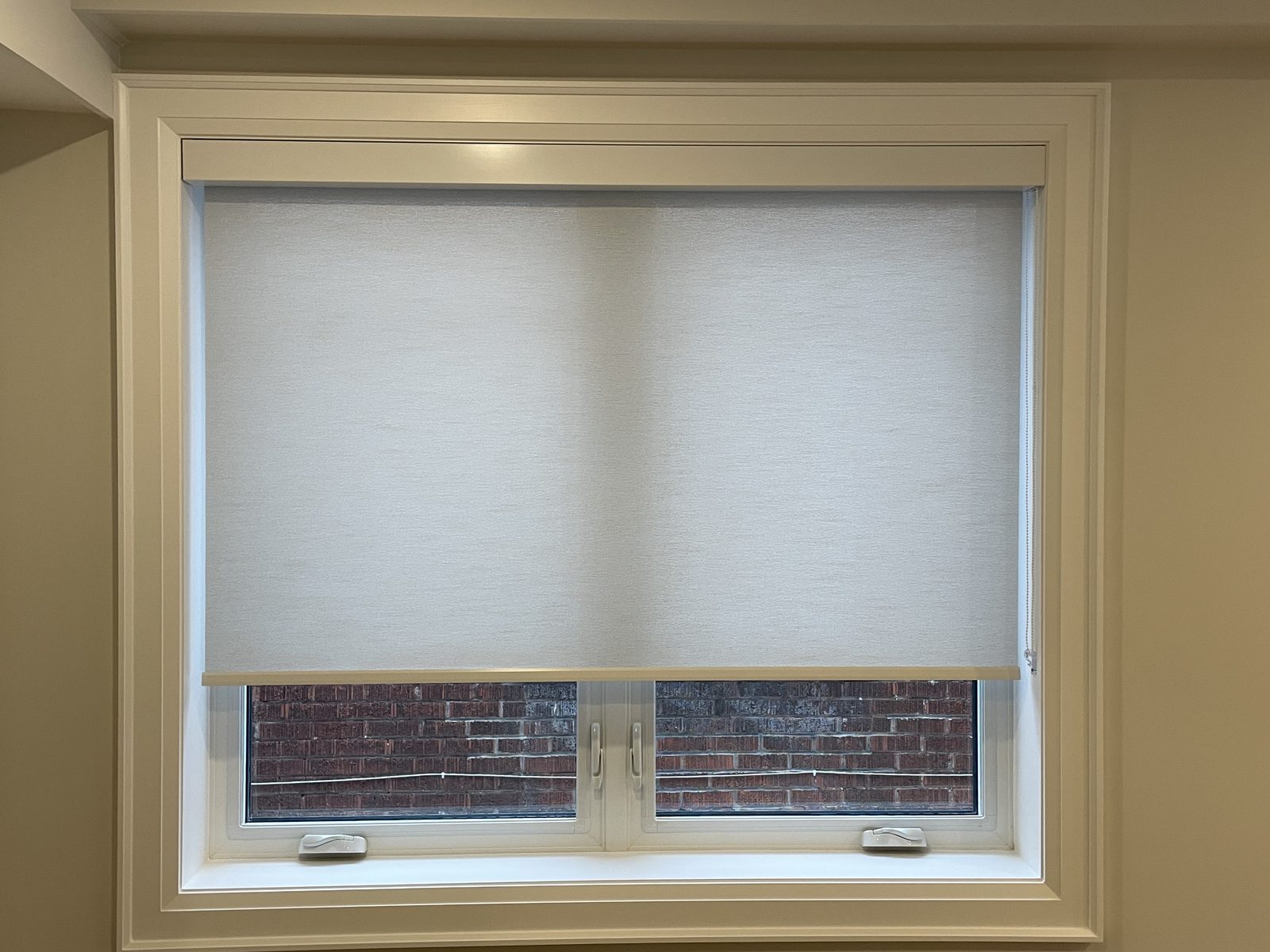 Deep-set window with a cream light-filtering roller shade fitted inside the frame under a fascia