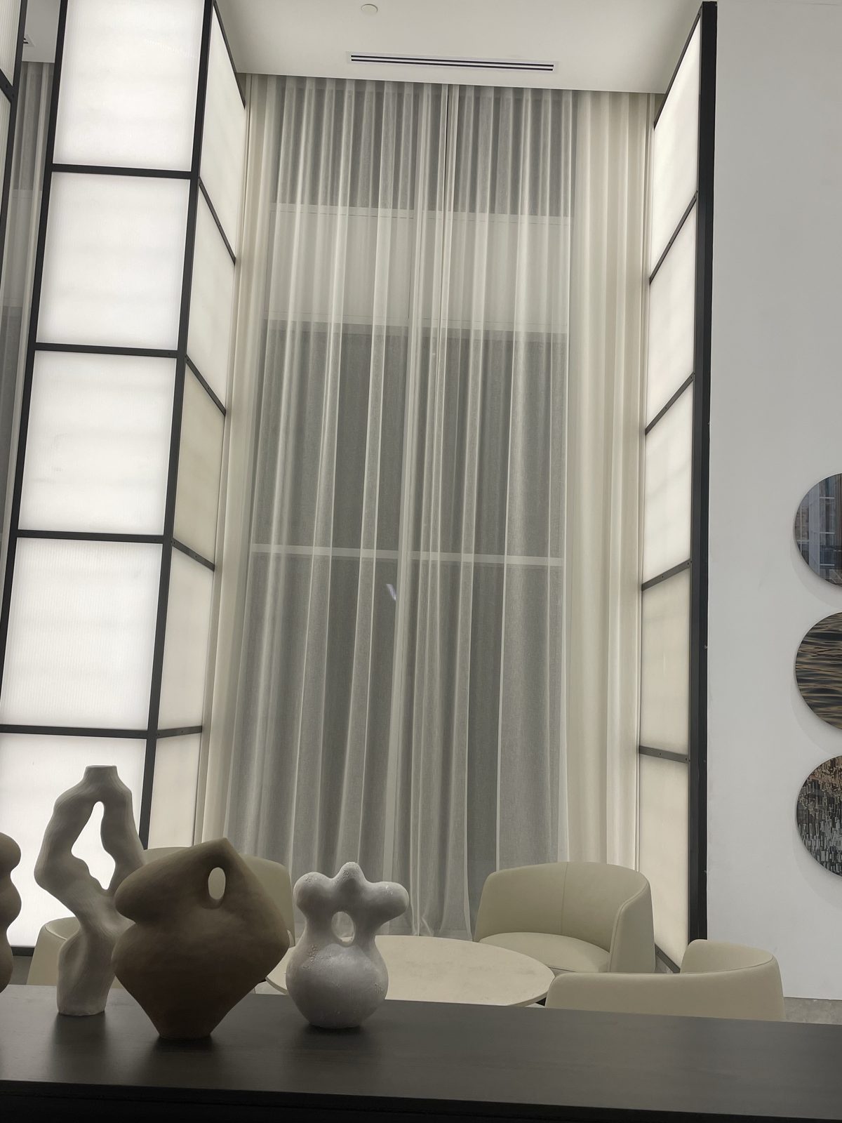 Lounge with full-height sheer drapery in a double-height window bay