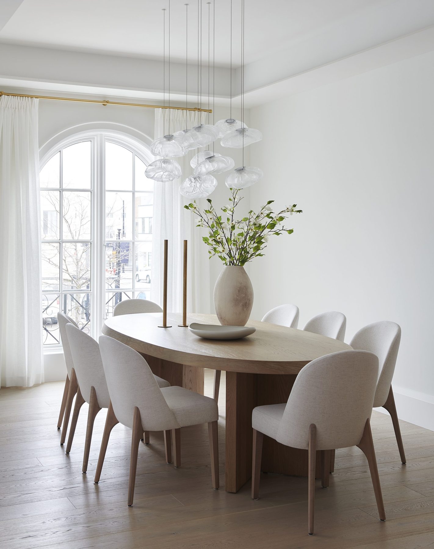 Dining room with arched windows and sheer drapery on a brass rod