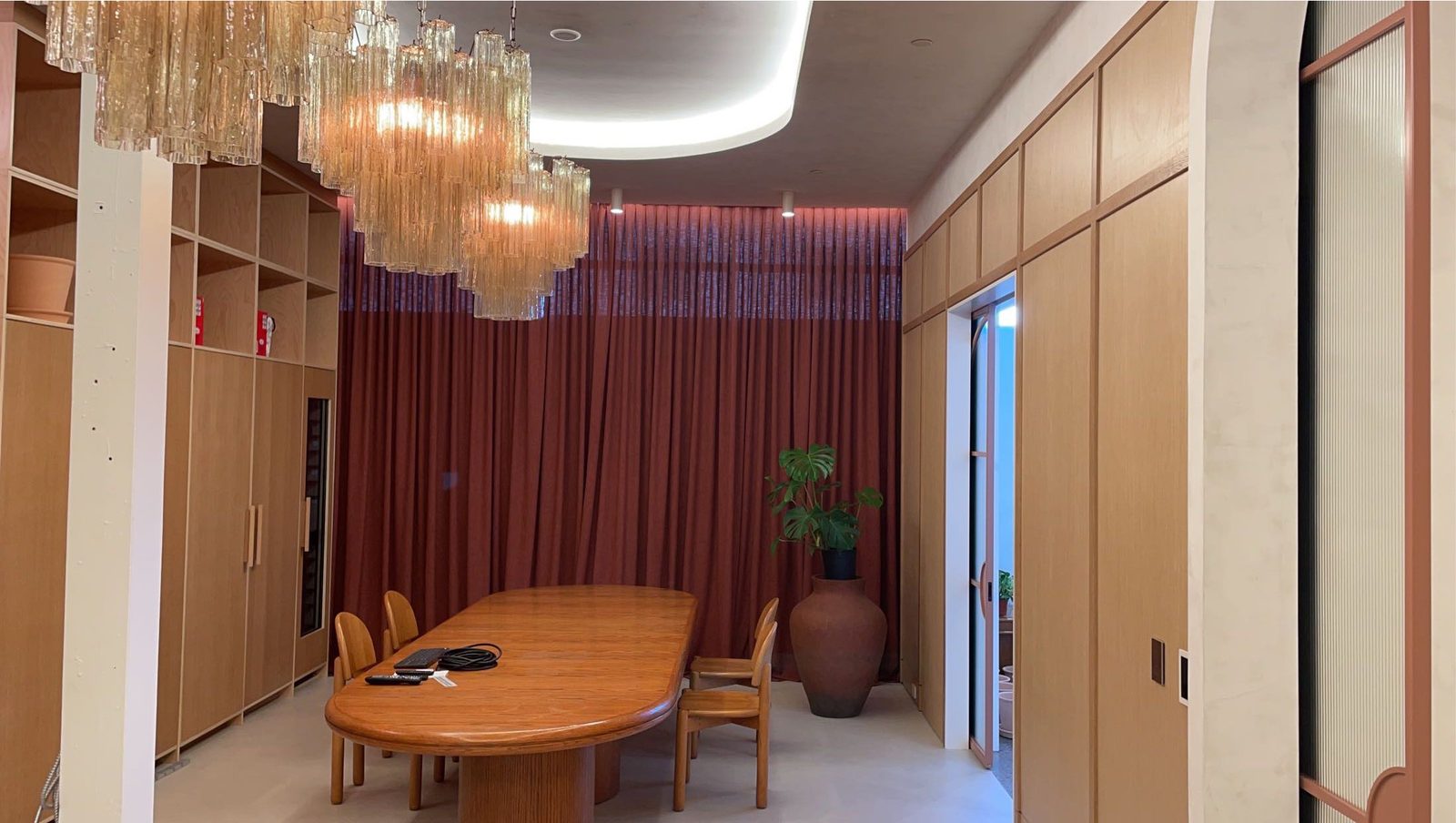 Dining room with rust drapery running wall to wall behind the table