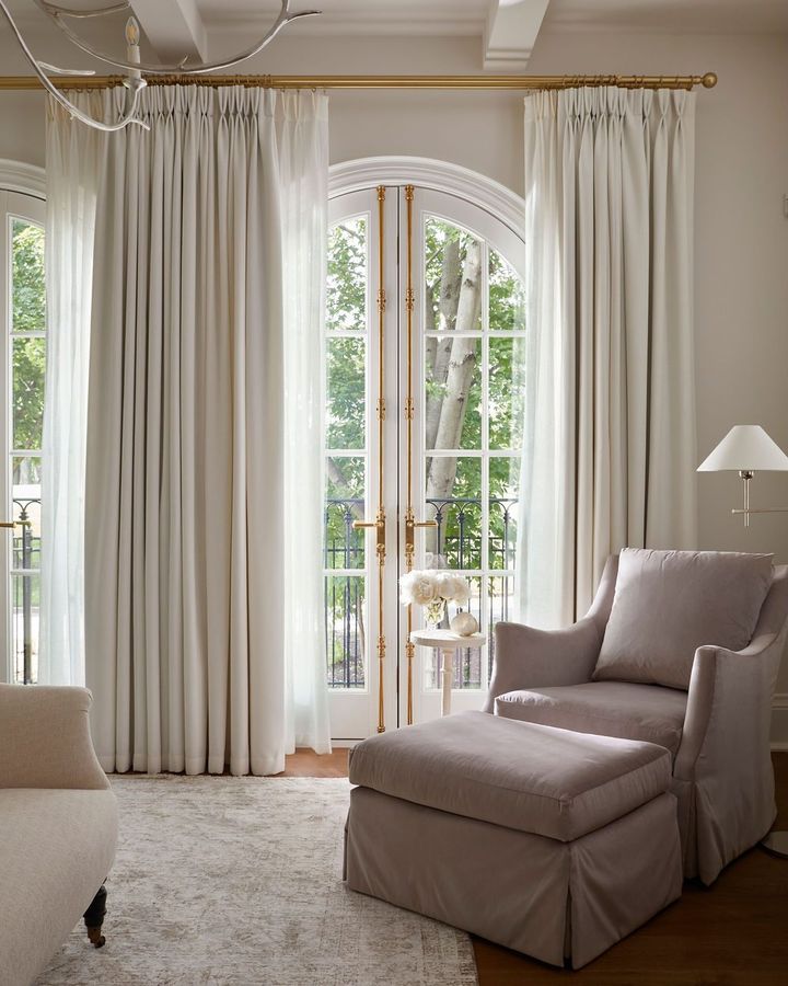 Pinch-pleat linen drapery on a brass rod above an arched French door