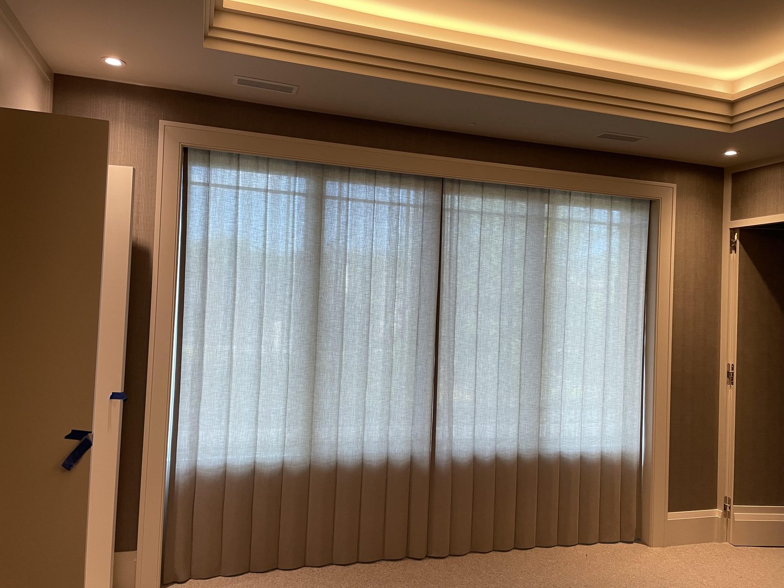 Family room with sheer ripple-fold panels drawn across a wide window opening