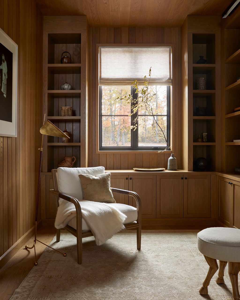 Wood-panelled library with a natural linen Roman shade