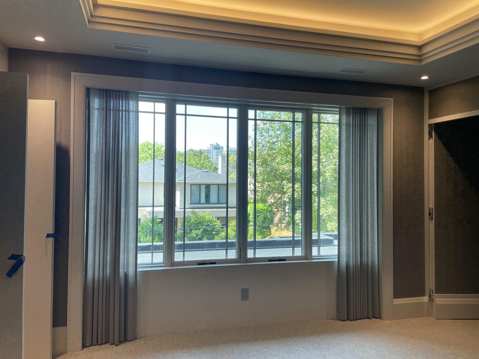 Grey sheer drapery drawn open either side of a wide picture window
