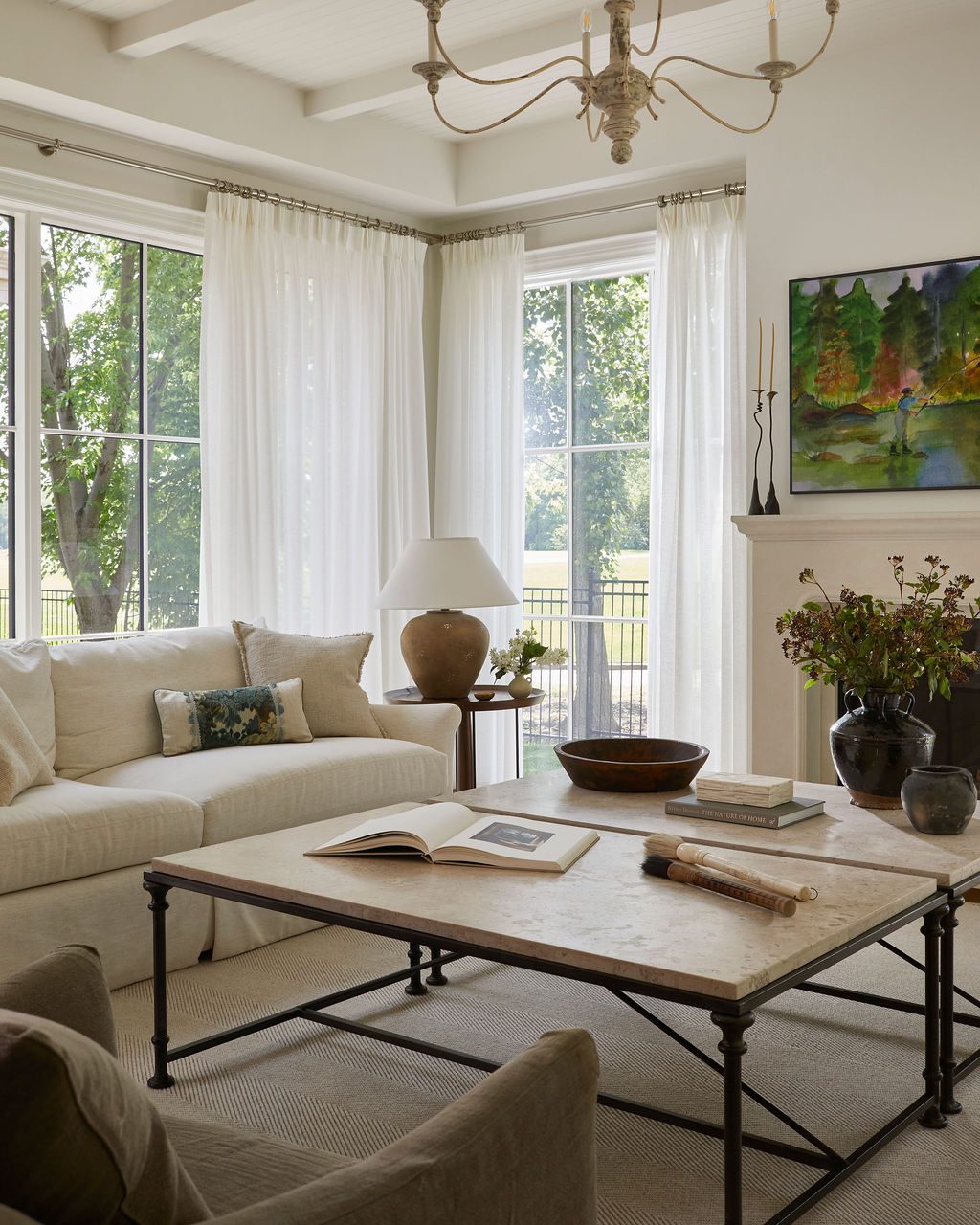 Living room with white sheer panels on corner windows beside a stone fireplace