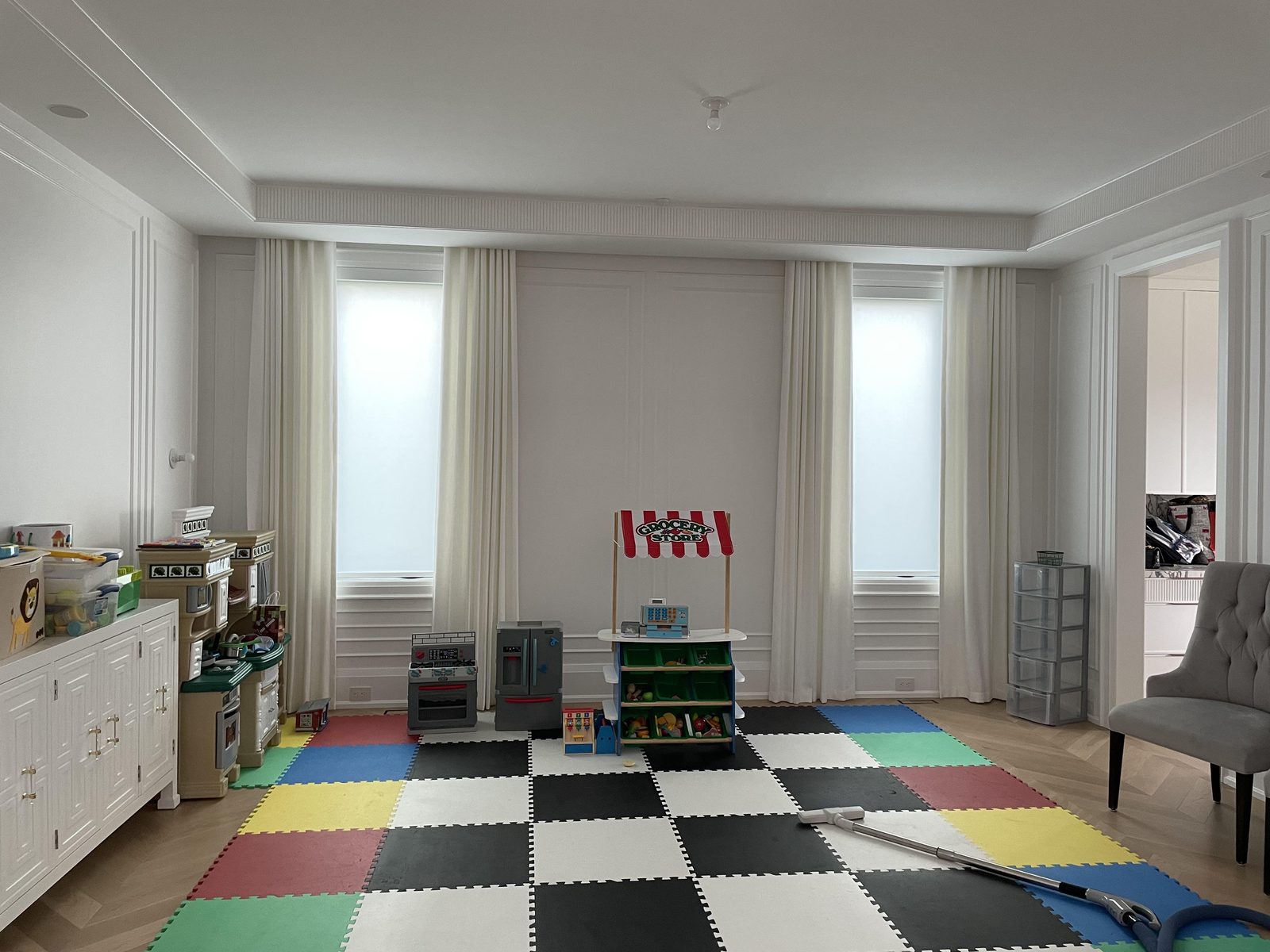 Playroom with ivory drapery panels either side of light-filtering roller shades