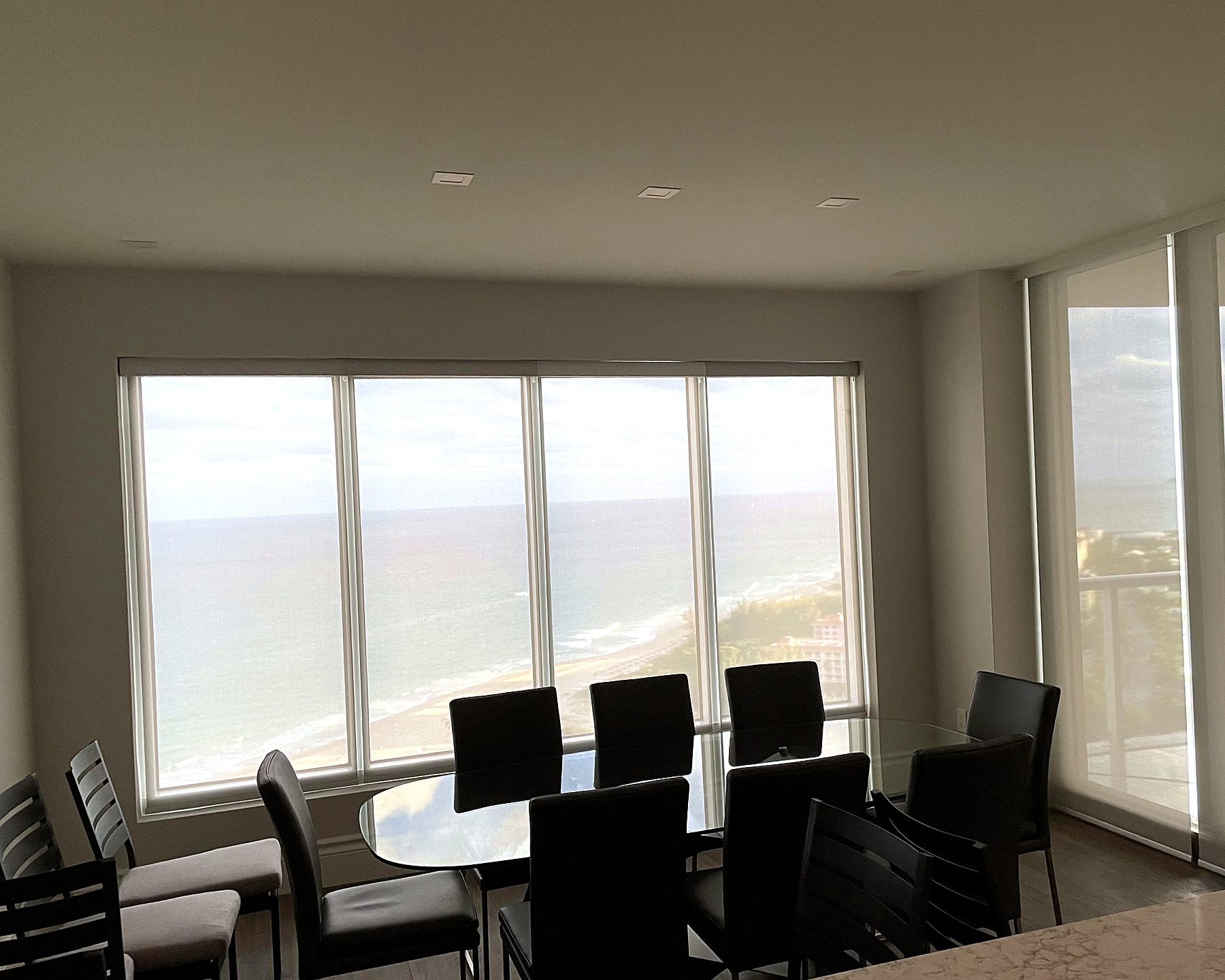 Dining area with solar screen shades over a water view